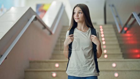 Téléchargez les photos : Jeune belle étudiante portant un sac à dos descendant les escaliers à l'école - en image libre de droit