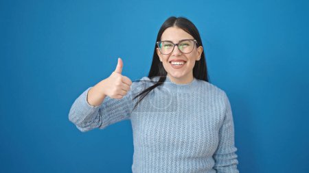 Photo for Young hispanic woman smiling with thumbs up over isolated blue background - Royalty Free Image