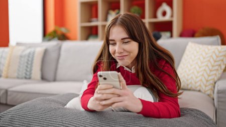 Photo for Young hispanic woman using smartphone lying on sofa at home - Royalty Free Image