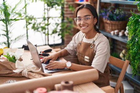 Photo for Young beautiful hispanic woman florist smiling confident using laptop at florist - Royalty Free Image
