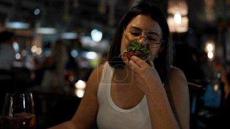 Photo for Young beautiful hispanic woman eating delicious italian food at the restaurant - Royalty Free Image
