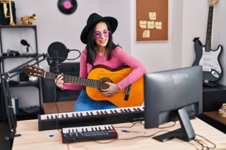 Téléchargez les photos : Jeune femme caucasienne musicien souriant confiant jouer de la guitare classique au studio de musique - en image libre de droit