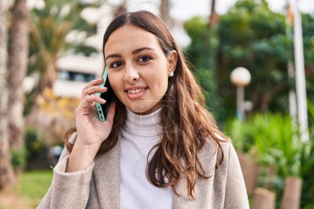 Téléchargez les photos : Jeune belle femme hispanique souriant confiant parler sur le smartphone au parc - en image libre de droit