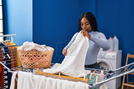 Foto de Mujer afroamericana colgando ropa en tendedero en la lavandería - Imagen libre de derechos