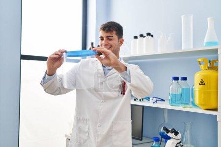 Photo for Young hispanic man scientist smiling confident holding screen mask at laboratory - Royalty Free Image