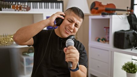 Photo for Striking portrait, serious young latin man, a professional musician, totally engrossed singing his song, unleashing his handsome voice in a music studio during a leisurely filled performance - Royalty Free Image