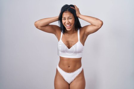 Photo for Hispanic woman wearing lingerie crazy and scared with hands on head, afraid and surprised of shock with open mouth - Royalty Free Image