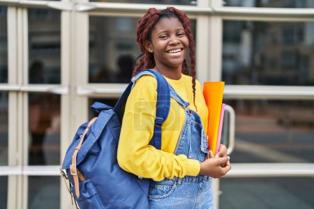Téléchargez les photos : African american woman student smiling confident holding books at university - en image libre de droit