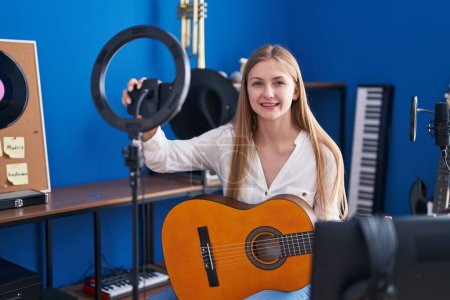 Téléchargez les photos : Young caucasian woman musician playing classical guitar record by smartphone at music studio - en image libre de droit