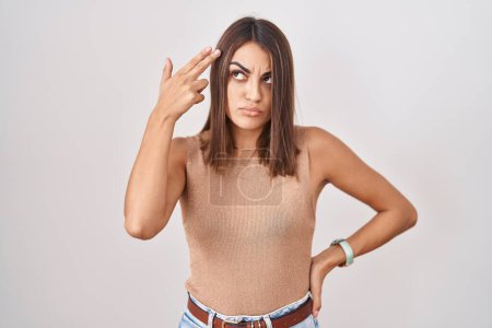 Foto de Young hispanic woman standing over white background shooting and killing oneself pointing hand and fingers to head like gun, suicide gesture. - Imagen libre de derechos