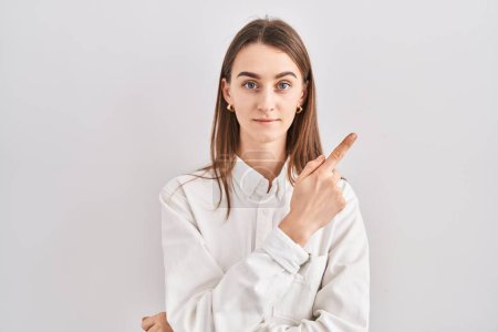 Téléchargez les photos : Jeune femme caucasienne debout sur fond isolé pointant avec le doigt de la main sur le côté montrant la publicité, visage sérieux et calme - en image libre de droit