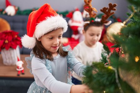 Téléchargez les photos : Adorable garçon et fille décorant l'arbre de Noël à la maison - en image libre de droit