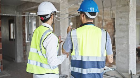 Téléchargez les photos : Deux constructeurs hommes debout en arrière parlant sur le chantier de construction - en image libre de droit