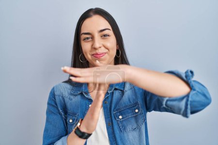 Téléchargez les photos : Femme hispanique debout sur fond bleu faire le temps geste avec les mains, visage frustré et sérieux - en image libre de droit