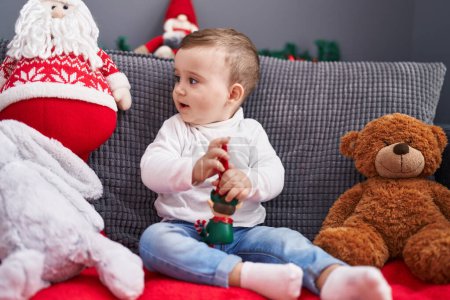Foto de Adorable bebé caucásico sentado en el sofá con decoración de Navidad en casa - Imagen libre de derechos