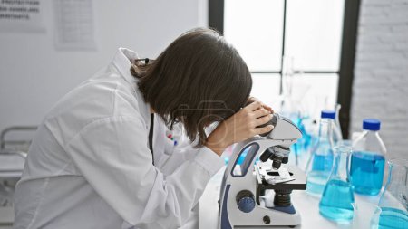 Téléchargez les photos : Jeune femme hispanique jeune scientifique utilisant le microscope au laboratoire - en image libre de droit