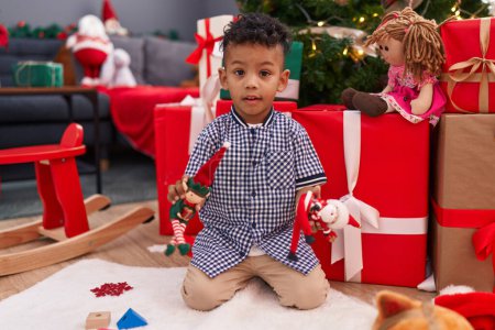 Téléchargez les photos : Africain américain garçon jouer avec des jouets assis sur le sol par des cadeaux de Noël à la maison - en image libre de droit