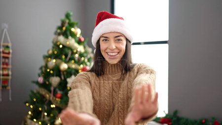 Photo for Young beautiful hispanic woman wearing christmas hat standing at home - Royalty Free Image