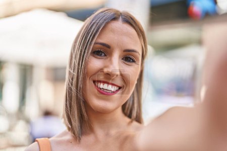 Téléchargez les photos : Jeune belle femme hispanique souriant confiant faire selfie par caméra à la rue - en image libre de droit
