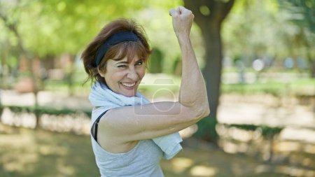 Téléchargez les photos : Femme d'âge moyen portant des vêtements de sport faisant un geste fort avec le bras au parc - en image libre de droit