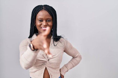 Foto de Mujer africana con trenzas de pie sobre fondo blanco sonriendo amigable ofreciendo apretón de manos como saludo y bienvenida. negocios exitosos. - Imagen libre de derechos
