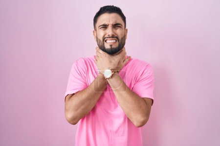 Photo for Hispanic young man standing over pink background shouting suffocate because painful strangle. health problem. asphyxiate and suicide concept. - Royalty Free Image
