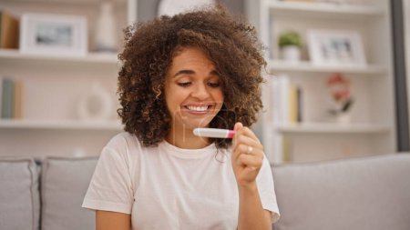 Photo for Young beautiful hispanic woman looking pregnancy test smiling at home - Royalty Free Image