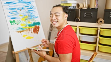 Photo for Confident young chinese man, beaming with joy, immersed in drawing at an art studio, mastering his craft while enjoying his artistic passion - Royalty Free Image