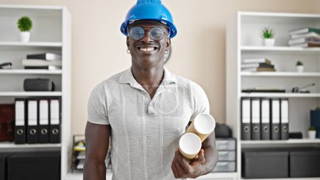 Photo for African american man architect smiling confident holding blueprints at the office - Royalty Free Image