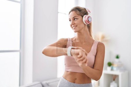 Téléchargez les photos : Young blonde woman listening to music using stopwatch at home - en image libre de droit