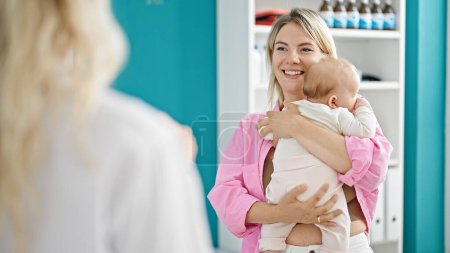 Photo for Mother and daughter hugging each other having medical consultation at clinic - Royalty Free Image