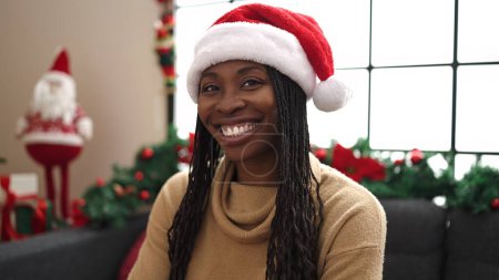 Photo for African woman smiling sitting by christmas decoration at home - Royalty Free Image