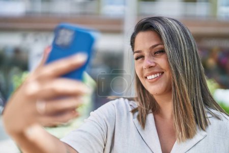 Téléchargez les photos : Jeune femme hispanique souriant confiant faire selfie par le smartphone à la rue - en image libre de droit