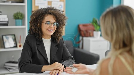 Foto de Joven hermosa mujer hispana agente de bienes raíces y cliente hablando en la oficina - Imagen libre de derechos