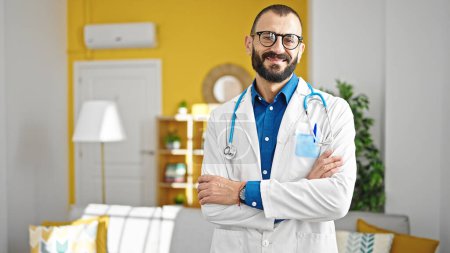 Photo for Young hispanic man doctor smiling confident standing with arms crossed gesture at clinic - Royalty Free Image