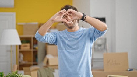 Foto de Joven hombre hispano haciendo un gesto de corazón en un nuevo hogar - Imagen libre de derechos