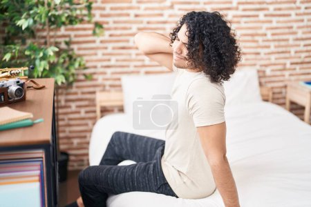 Photo for Young latin man suffering for neck injury sitting on bed at bedroom - Royalty Free Image