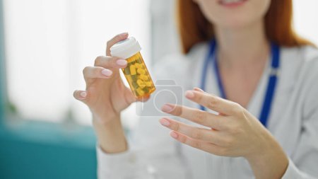 Téléchargez les photos : Jeune rousse femme médecin prescrivant des pilules à la clinique - en image libre de droit