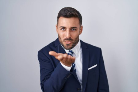 Photo for Handsome hispanic man wearing suit and tie looking at the camera blowing a kiss with hand on air being lovely and sexy. love expression. - Royalty Free Image