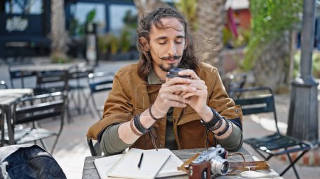 Photo for Young hispanic man tourist drinking coffee sitting on table at coffee shop terrace - Royalty Free Image