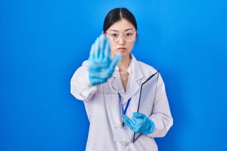 Photo for Chinese young woman working at scientist laboratory doing stop sing with palm of the hand. warning expression with negative and serious gesture on the face. - Royalty Free Image