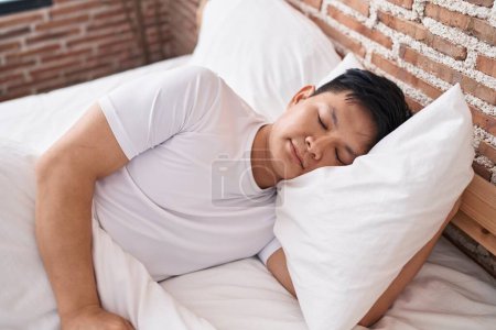 Téléchargez les photos : Jeune homme chinois couché sur le lit dormant dans la chambre - en image libre de droit