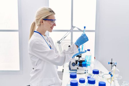 Téléchargez les photos : Jeune femme blonde scientifique analysant des éprouvettes en laboratoire - en image libre de droit