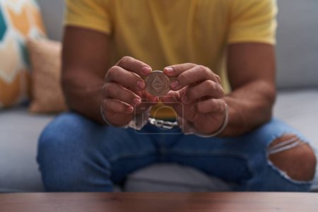 Téléchargez les photos : Jeune homme hispanique criminel tenant éthérie crypto monnaie classique portant des menottes à la maison - en image libre de droit