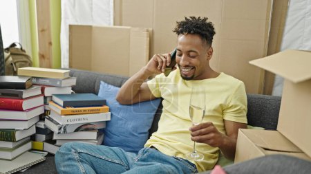 Téléchargez les photos : Africain américain parler sur smartphone boire du champagne à la nouvelle maison - en image libre de droit
