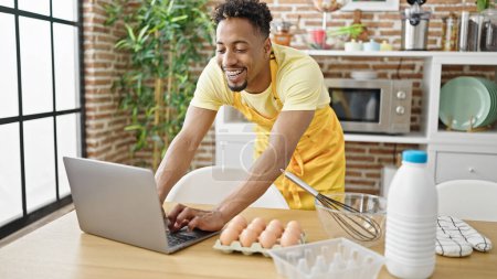 Photo for African american man chef looking online recipe on laptop at dinning room - Royalty Free Image