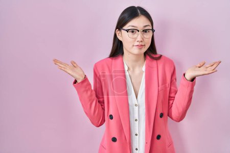 Photo for Chinese business young woman wearing glasses clueless and confused expression with arms and hands raised. doubt concept. - Royalty Free Image