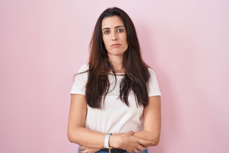 Photo for Young brunette woman standing over pink background relaxed with serious expression on face. simple and natural looking at the camera. - Royalty Free Image
