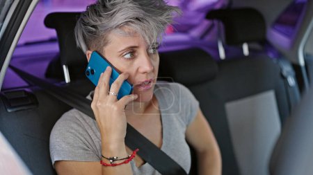 Foto de Mujer joven pasajero sentado en el coche hablando en el teléfono inteligente en la calle - Imagen libre de derechos
