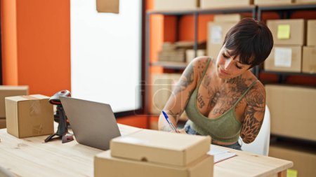 Téléchargez les photos : Femme hispanique avec amputé bras ecommerce travailleur d'affaires en utilisant l'écriture d'ordinateur portable sur le document au bureau - en image libre de droit